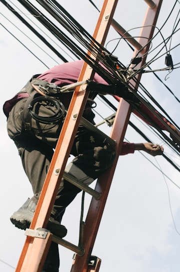 Electrician installing structured cabling in a modern office space with tools and safety gear.