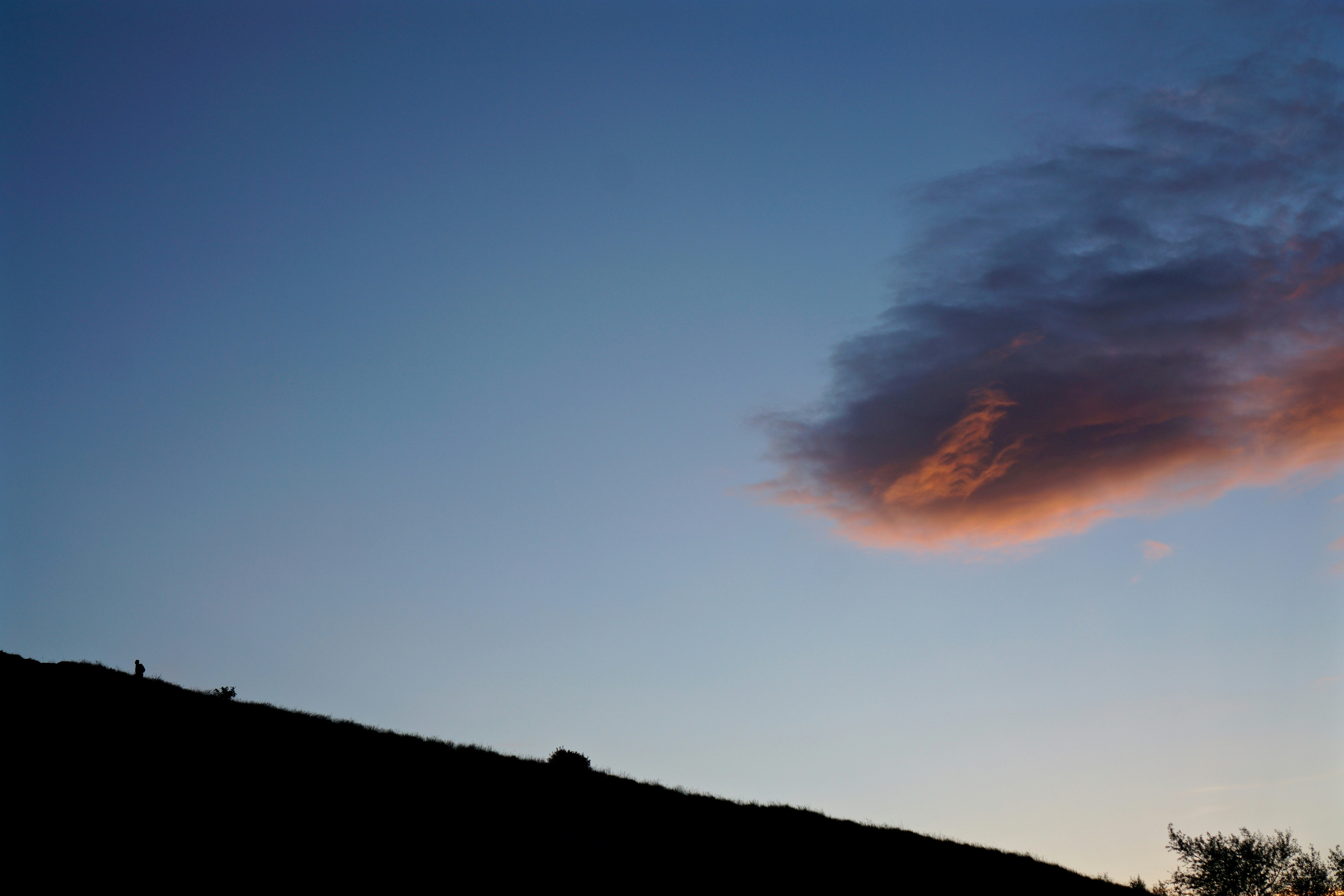 silhouette of mountain slope under cloudy sky