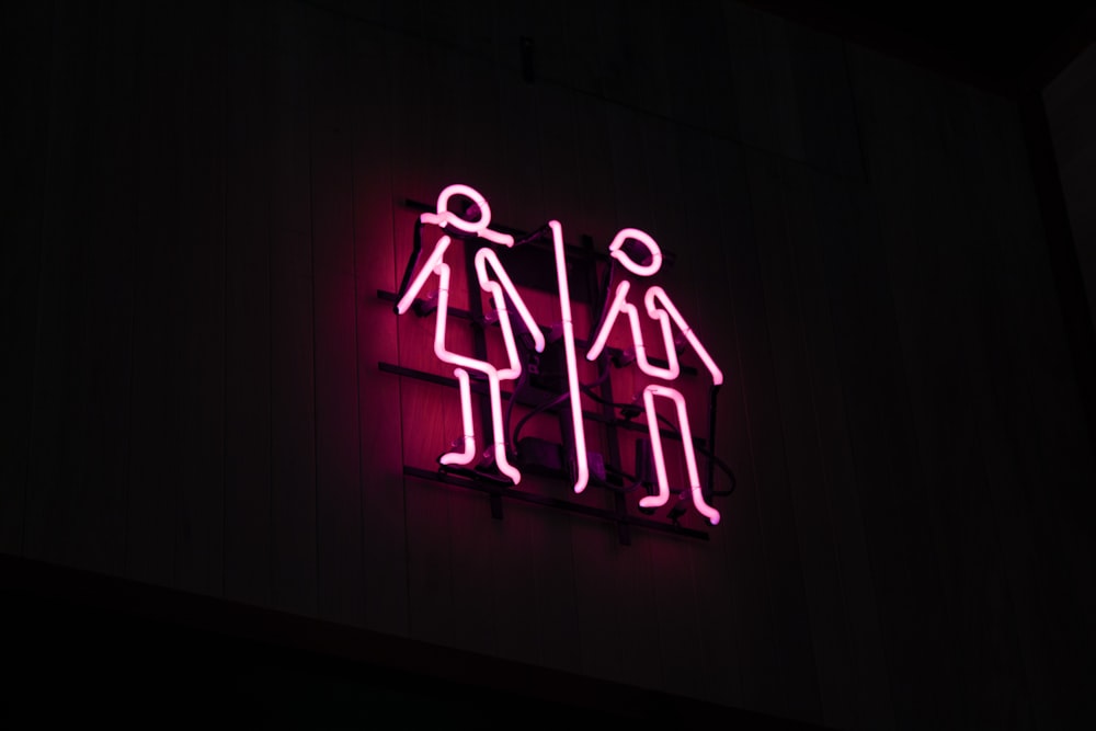 man and woman neon signage at dark area