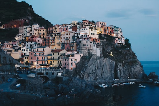 building on rock near body of water at blue hour in Parco Nazionale delle Cinque Terre Italy