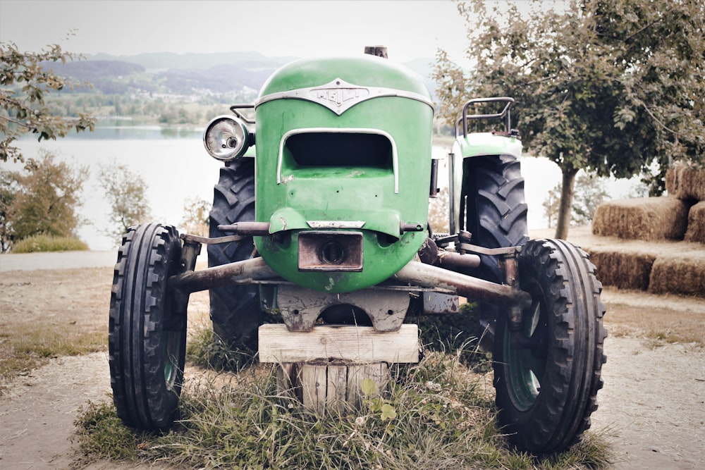 Photographie sélective de la mise au point du tracteur vert près d’un plan d’eau