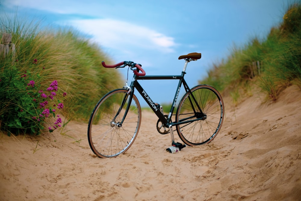 Bicicleta de carretera Pearson negra sobre arena marrón