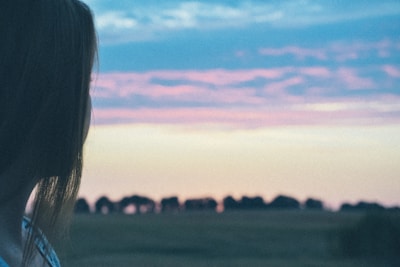 A serene moment featuring an anime character gazing at a sunset over a futuristic cityscape.