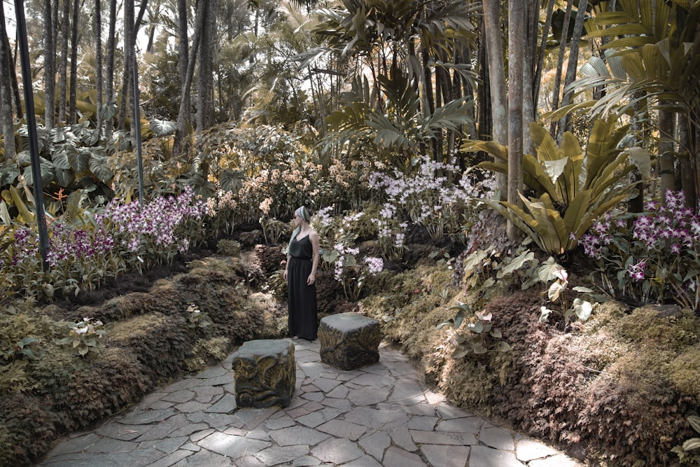 woman in black dress standing near pink flowers