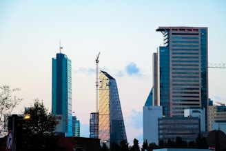 A sleek, sunlit skyline featuring under-construction and completed modern residential and commercial buildings.