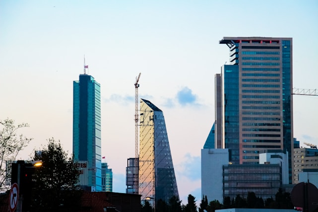 A sleek, sunlit skyline featuring under-construction and completed modern residential and commercial buildings.