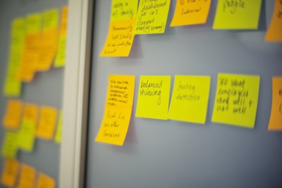 Close-up of hands writing ideas on sticky notes in a bright, creative workspace.