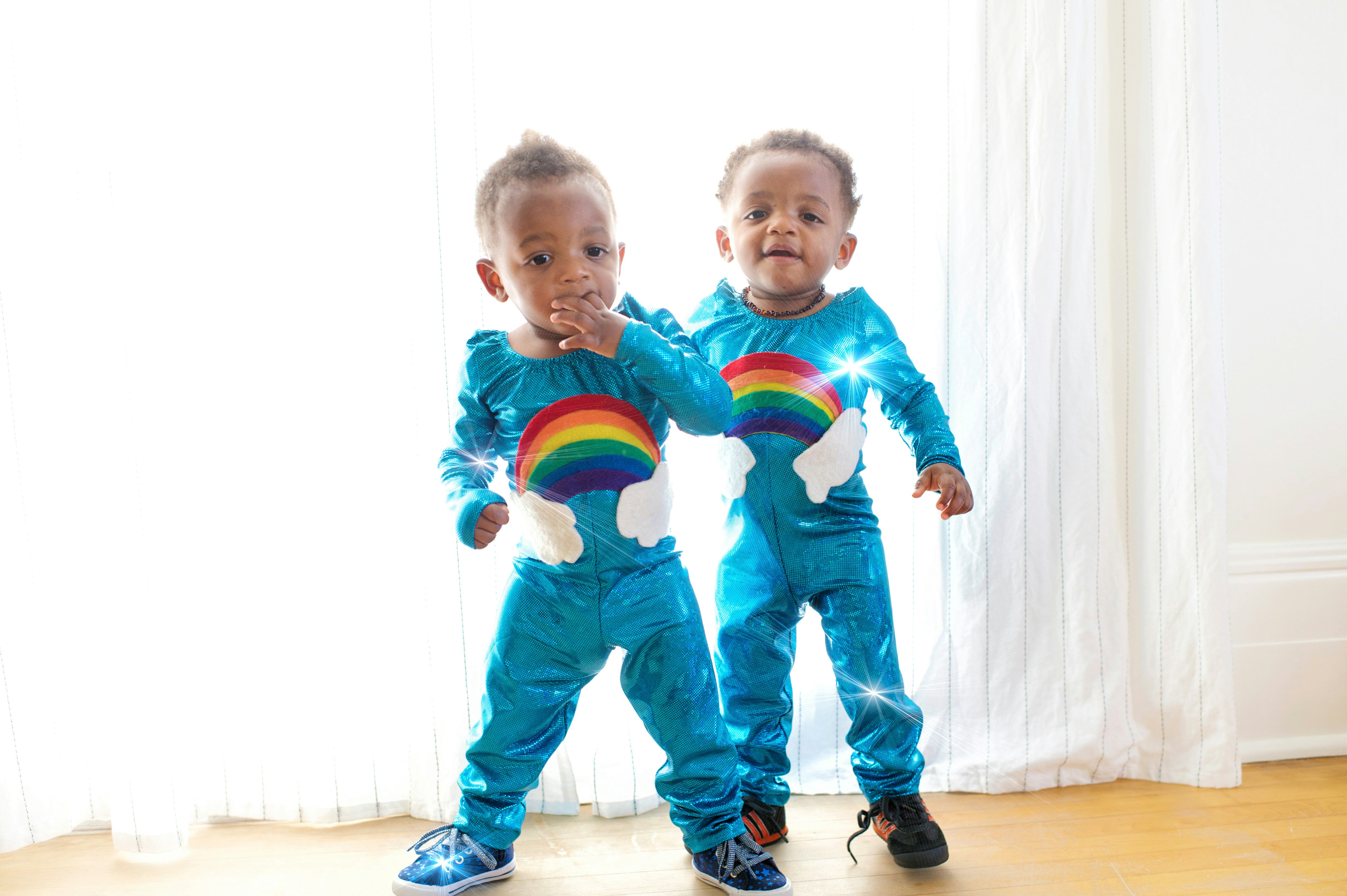 two toddler's standing in front of white window curtain