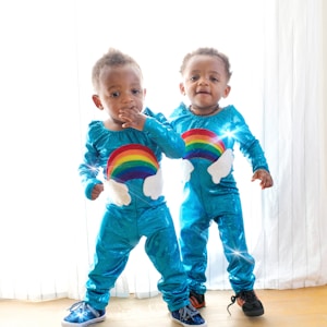 two toddler's standing in front of white window curtain