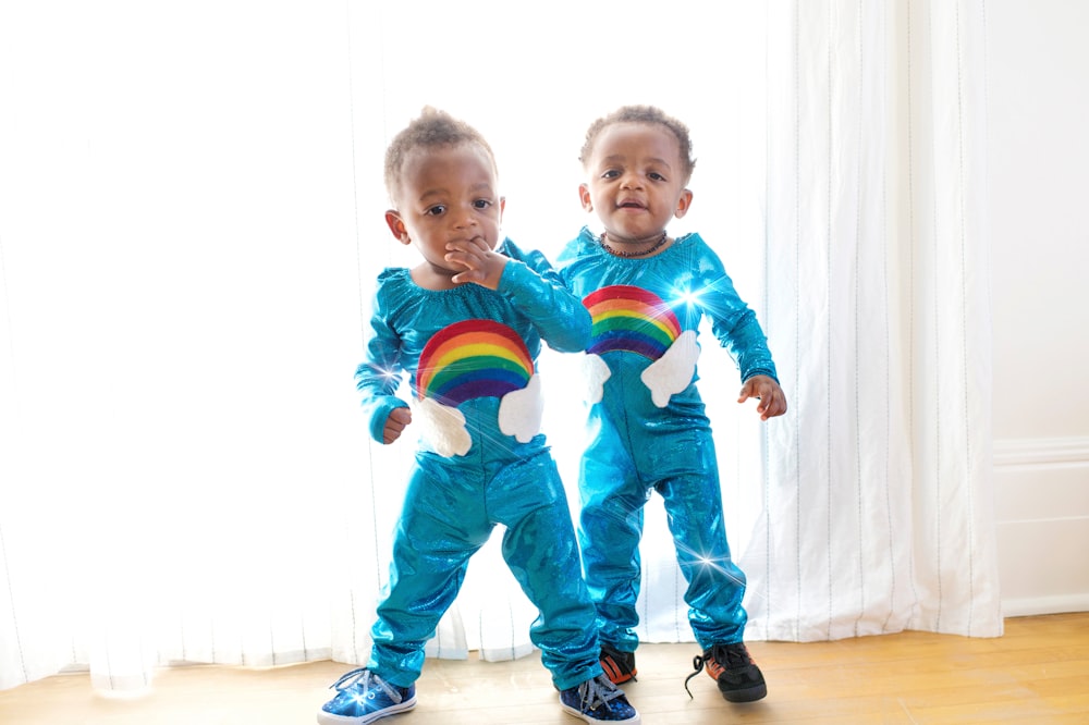 Dos niños pequeños de pie frente a la cortina blanca de la ventana