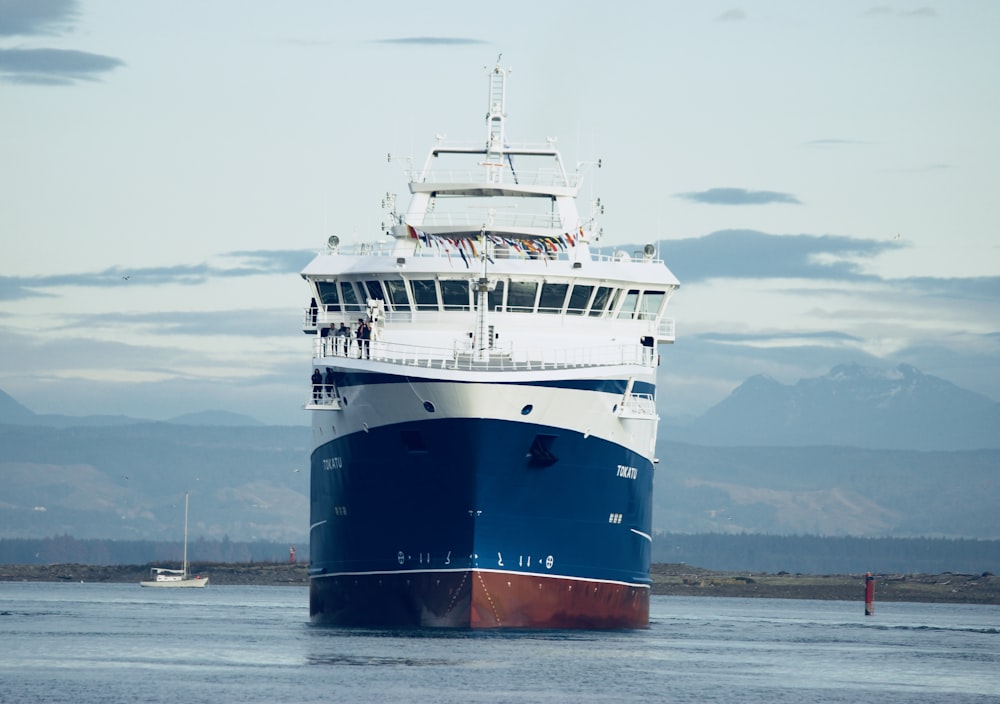 white and blue ship on water with mountain background