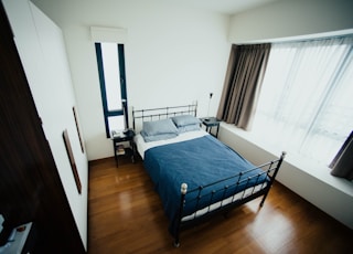 blue and white bed sheet and black bed frame in room