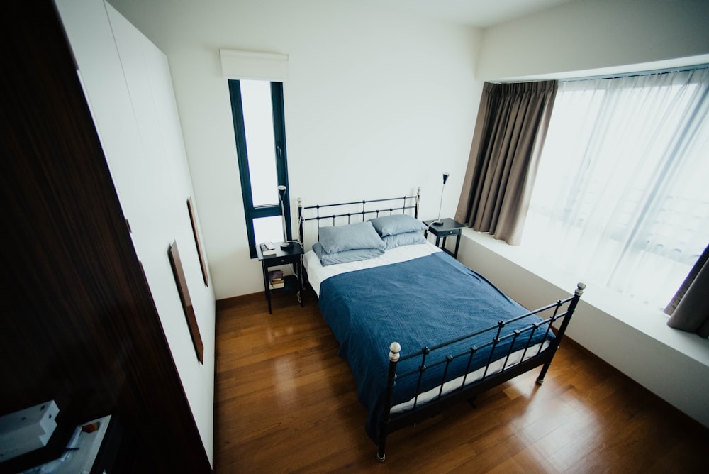 blue and white bed sheet and black bed frame in room