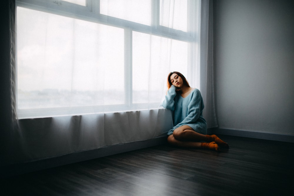 woman sitting on floor near window