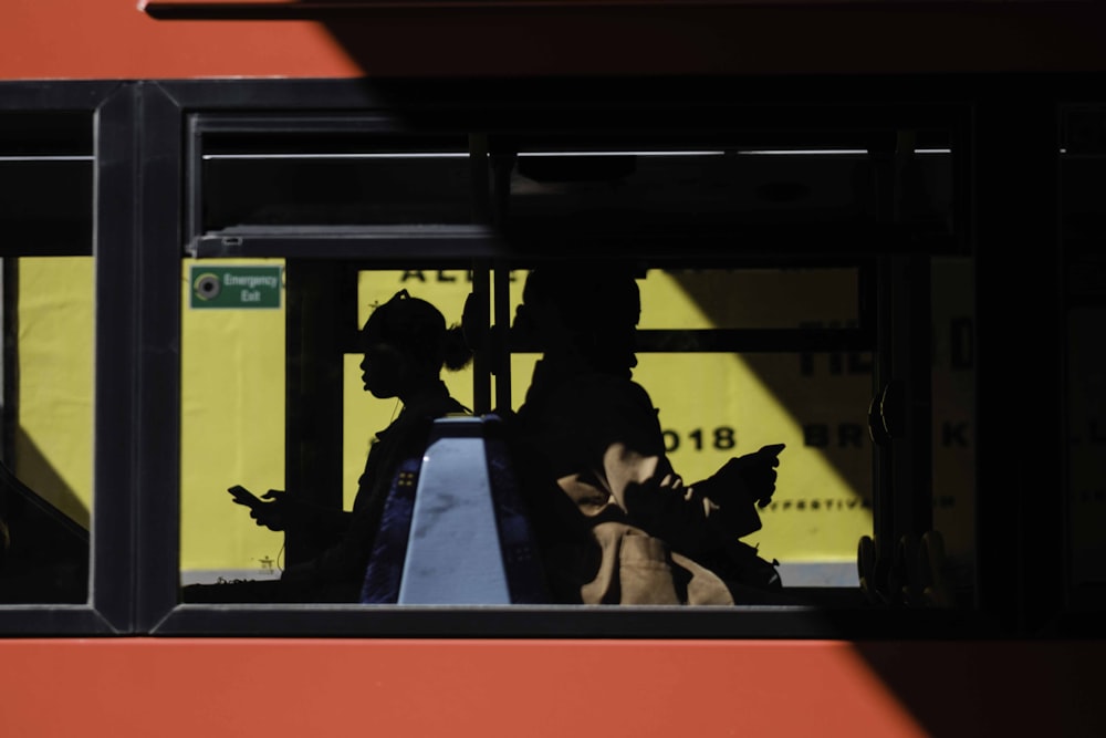 people inside bus sitting while using smartphone