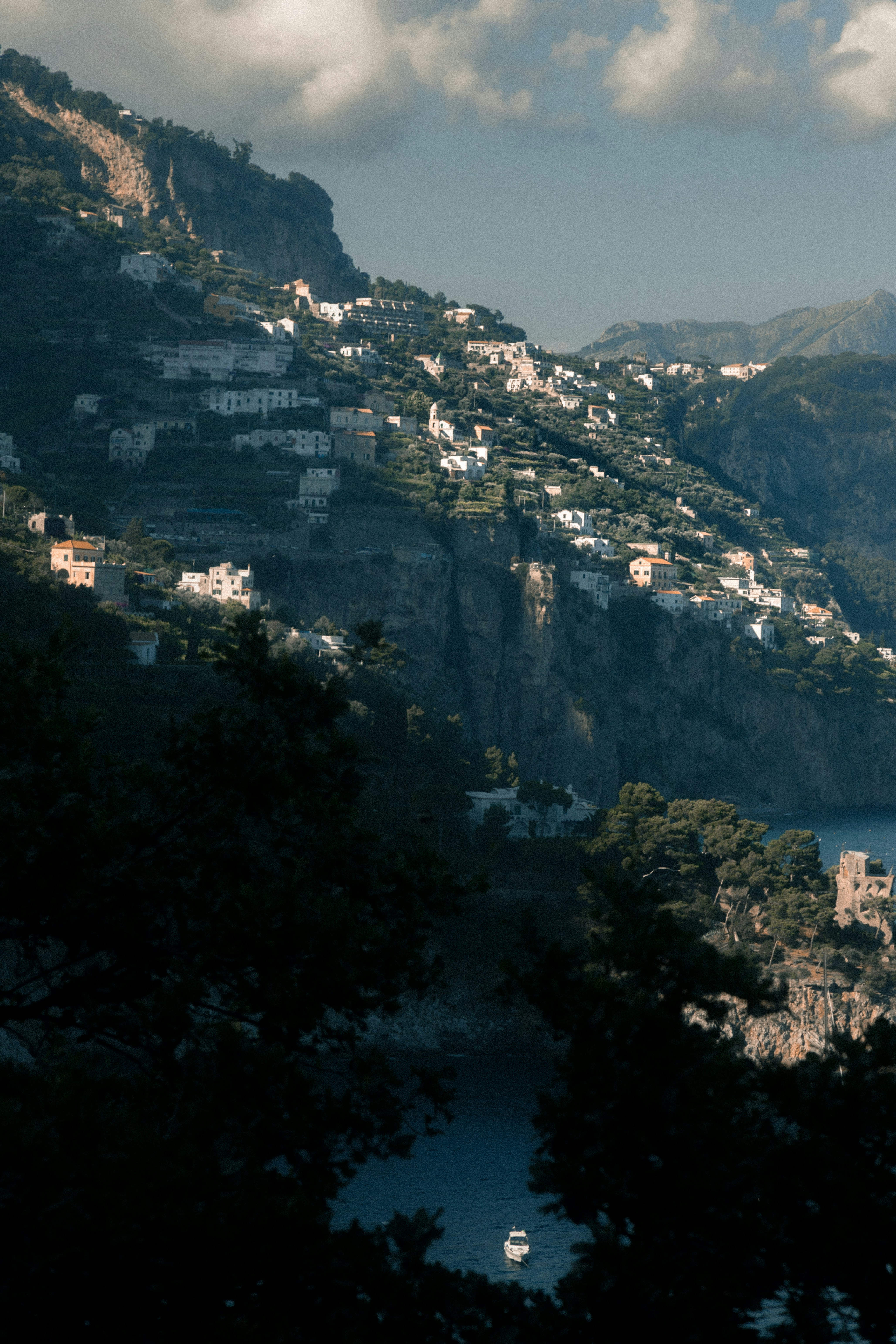 white boat on body of water near houses on cliff