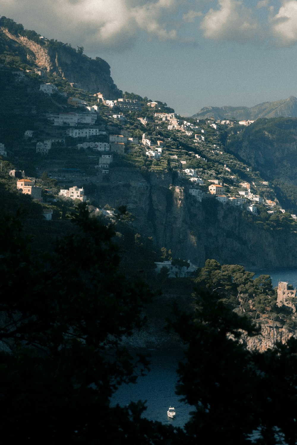 white boat on body of water near houses on cliff
