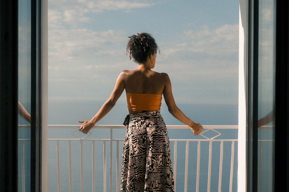 Frau mit orangefarbener Röhre und schwarzem Rock mit Blick auf die Terrasse