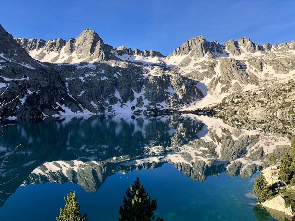 snow filled mountain near body of water