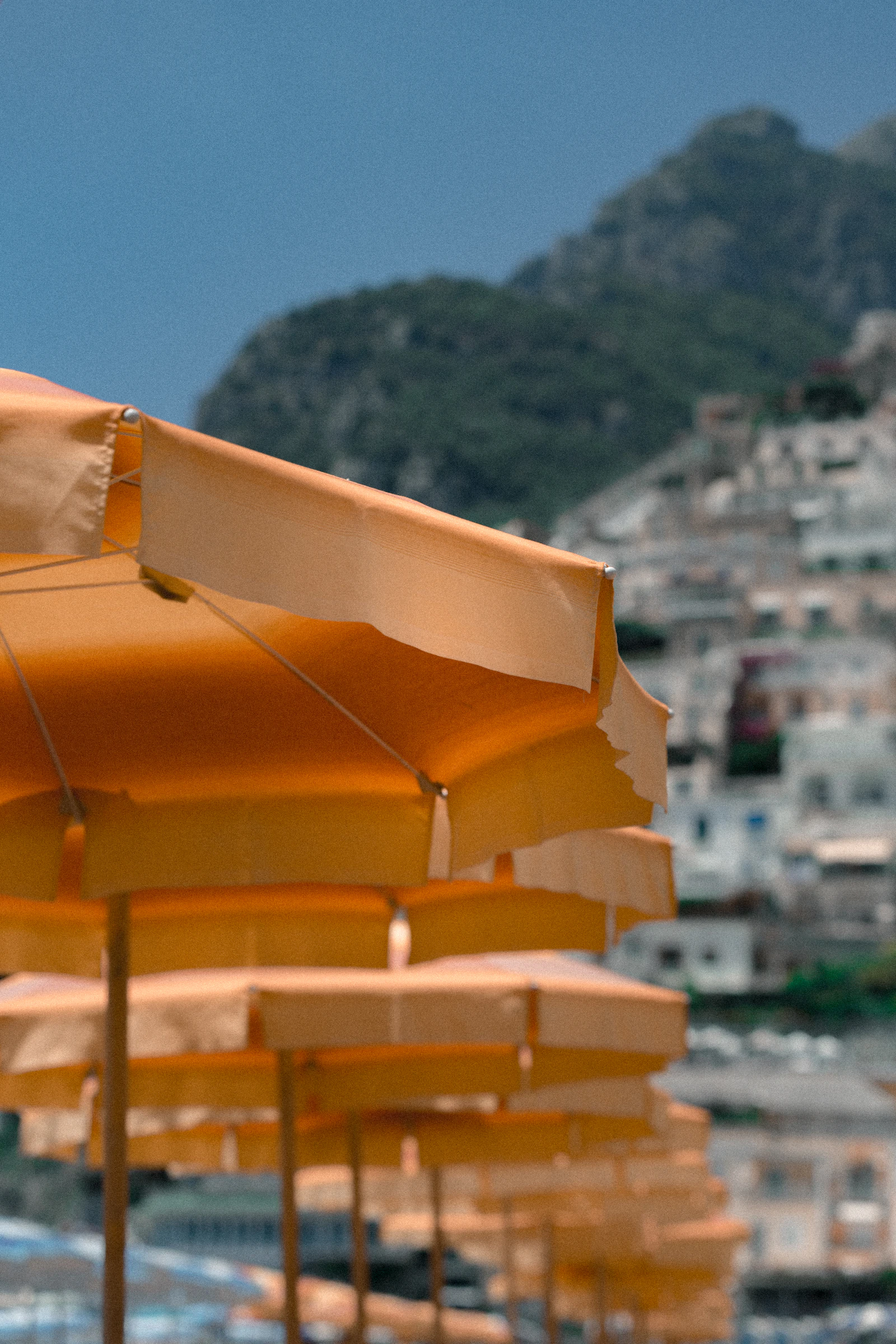 Orange beach umbrellas on a sunny beach in Positano, Italy