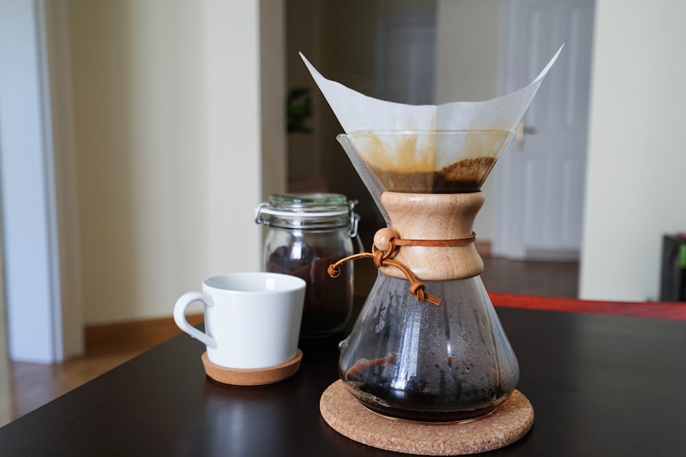 white ceramic teacup beside coffee carafe on table