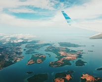 A scenic airplane flying over turquoise ocean waters near tropical islands.