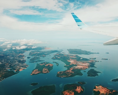 A scenic airplane flying over turquoise ocean waters near tropical islands.