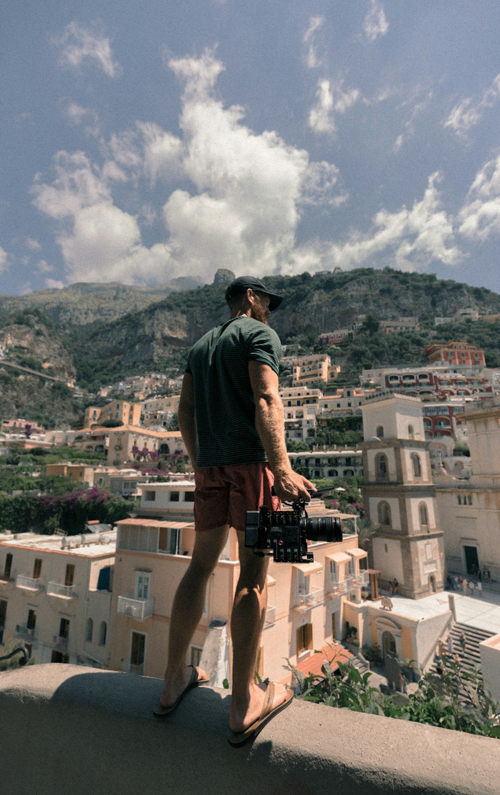 man standing on concrete wall near buildings during daytime