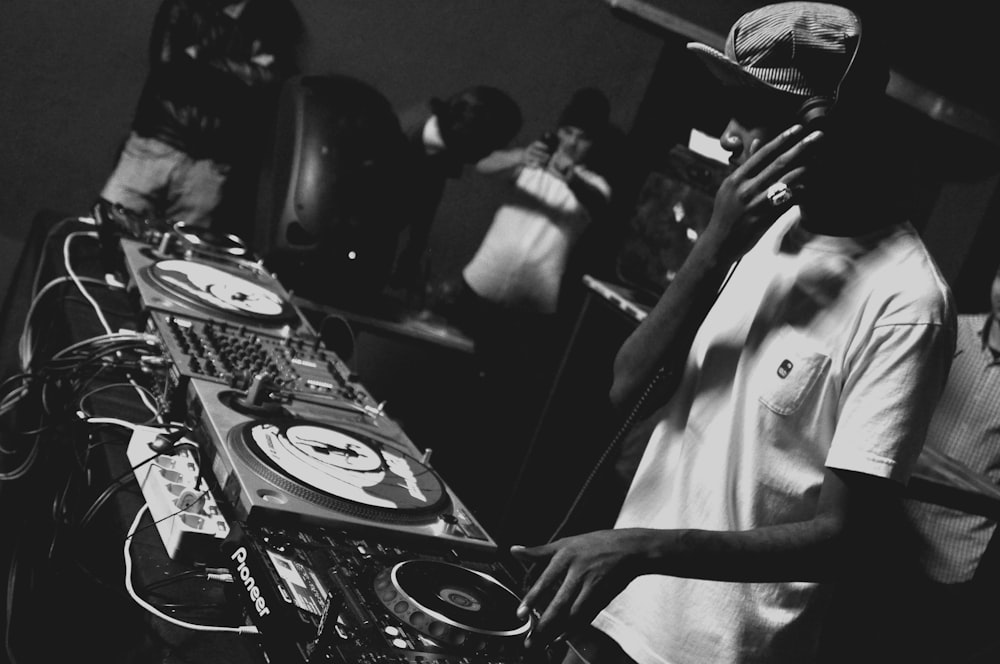 grayscale photo of man playing DJ mixing console