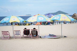 Guests relaxing on the beach with lounge chairs and umbrellas.