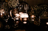 Softly lit personalized candles with delicate gold accents on a cream linen table.