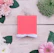 Flat lay of elegant lash packaging surrounded by soft pink roses on a marble surface.