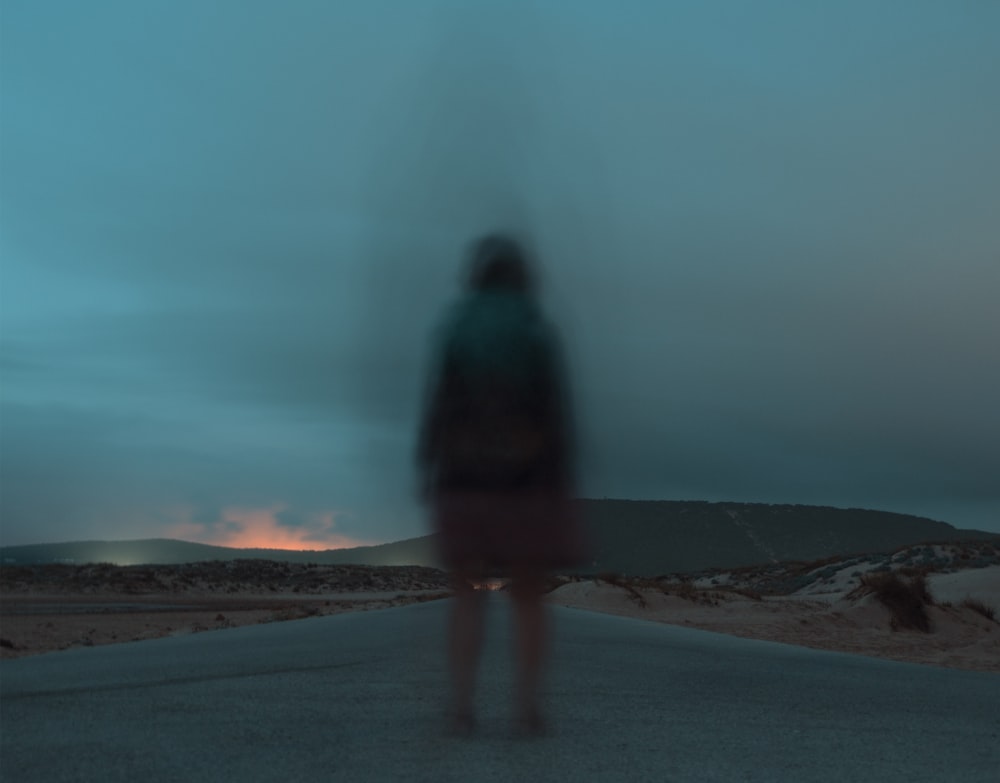 silhouette of person standing under cloudy sky