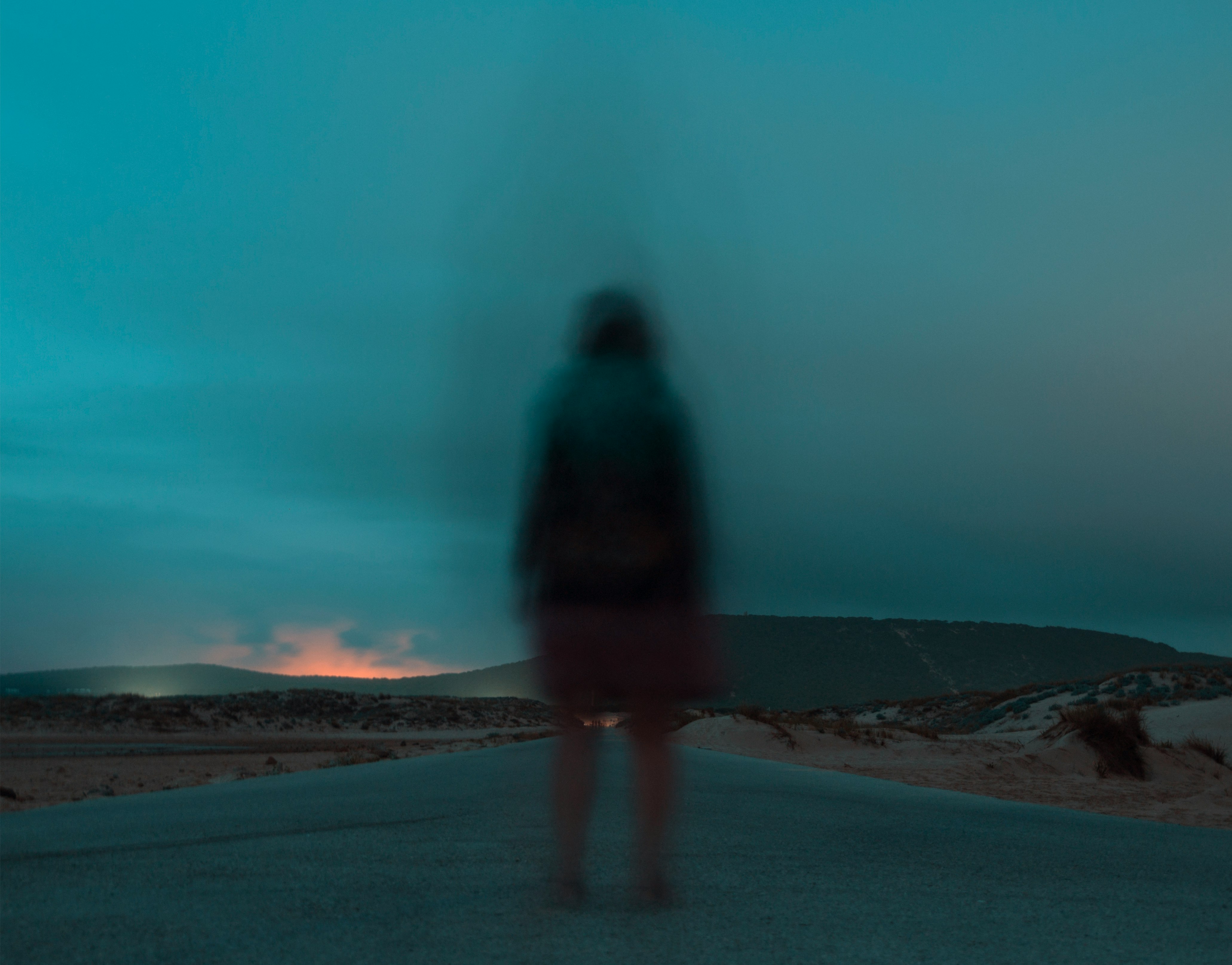 silhouette of person standing under cloudy sky