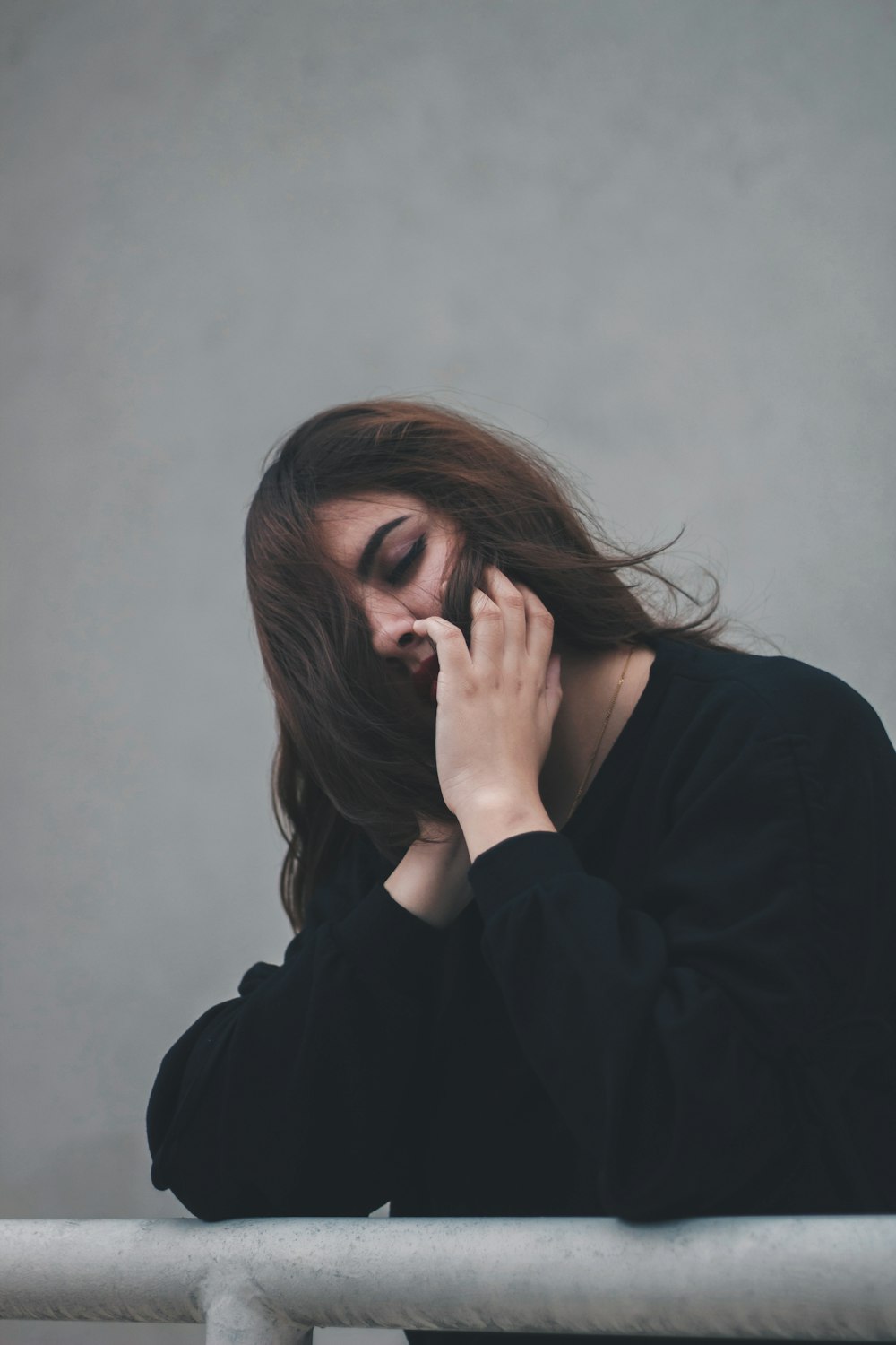 Mujer descansando en barandilla de metal gris cerca de pared gris