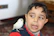 A cheerful 14-year-old boy holding a sushi roll with a colorful swifty bird perched on his shoulder.