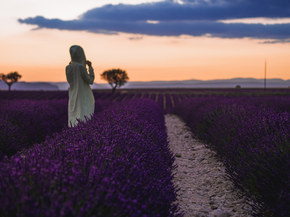 mujer de pie frente a las flores púrpuras