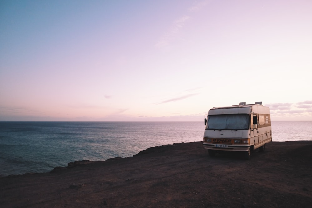 RV parked beside the edge of island during sunset