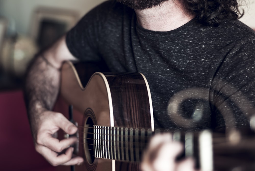 person playing brown acoustic guitar