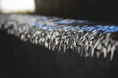 Close-up of iridescent mosaic shards reflecting sunlight.