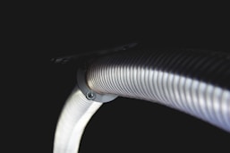Close-up of shiny metallic flexible interlock hoses coiled neatly in a workshop setting.