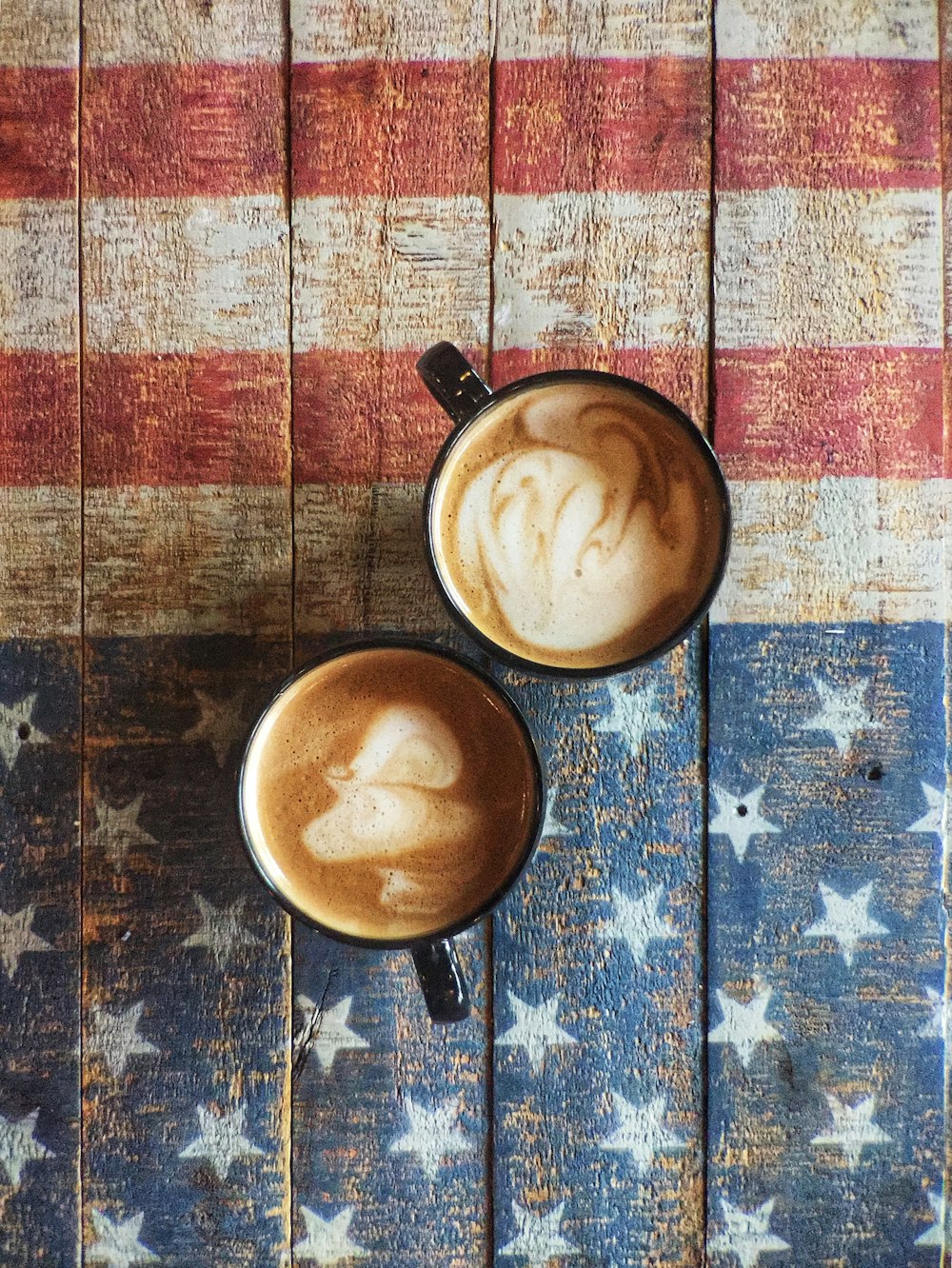 two black ceramic mugs full of coffees