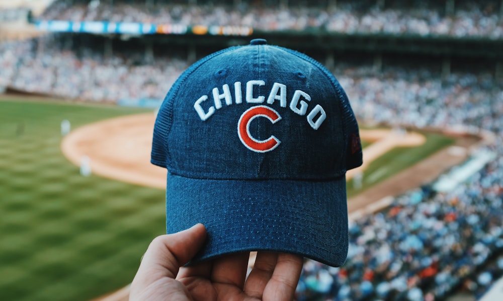 persona sosteniendo una gorra azul de los Chicago Cubs