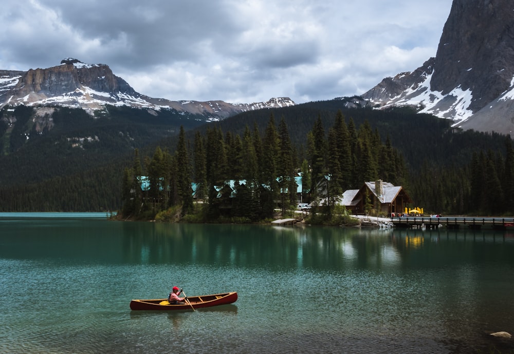 person rowing at lake during cloudy skies