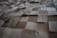 A textured surface composed of various square wooden tiles arranged in a grid pattern. Each tile has distinct grain patterns and shades, creating a three-dimensional appearance.