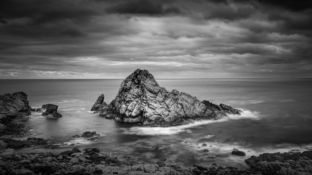 gray scale photo of rock formation beside sea