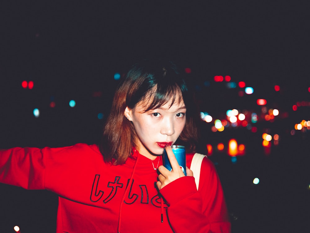 a woman in a red jacket is holding a cell phone