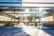 An Apple retail store with large glass windows and a prominent Apple logo above the entrance. Inside, there are wooden tables with electronic devices displayed along with colorful artwork on the walls. The bright, modern space is filled with natural light.