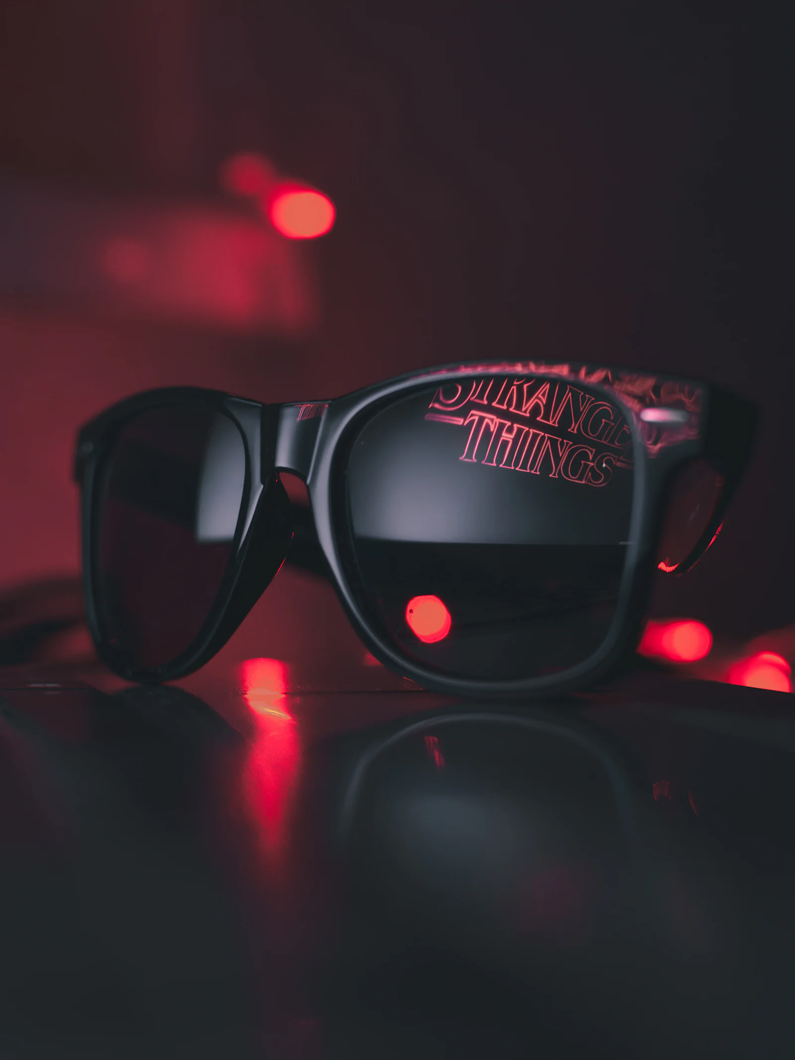 Dark framed sunglasses resting on a black surface.