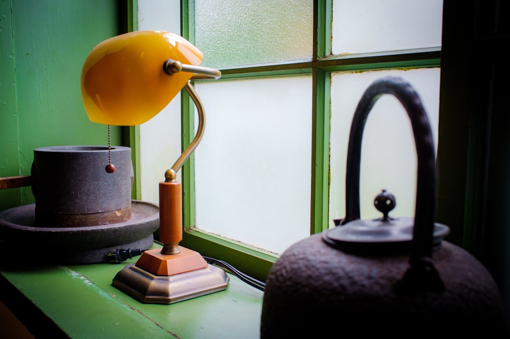 orange bankers lamp near to glass window